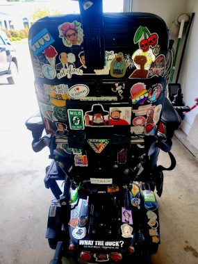 Image of the back of Dani's powerchair with stickers all over the back