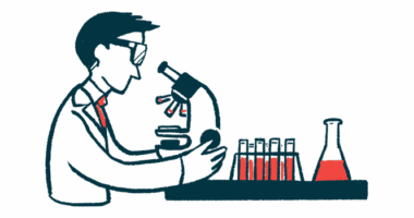 A scientist looks into a microscope, with a rack of half-filled vials nearby.
