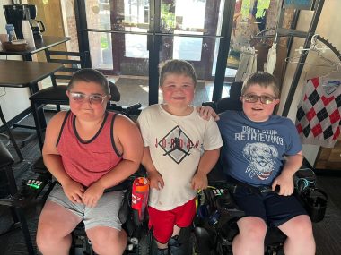 legacy of love | Muscular Dystrophy News | A photo of Betty's three sons with Duchenne MD. Rowen and Max are both seated in wheelchairs while Charlie stands in between them.
