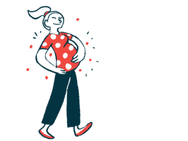 A smiling pregnant woman walks cradling her belly.