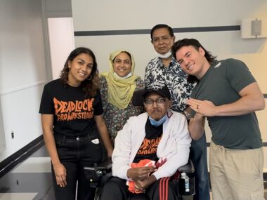 A family of four poses for a photo with a wrestler.