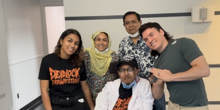 A family of four poses for a photo with a wrestler.