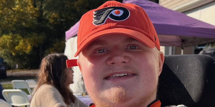 A close-up photo shows a man wearing a Philadelphia Flyers baseball cap.