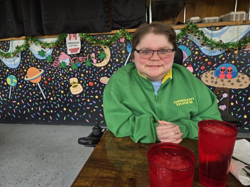 A man wearing glasses sits at a table at a restaurant.